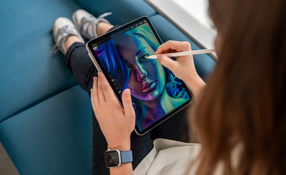 iPadを膝の上に置き、Apple Pencilを使ってProcreateアプリで絵を描いている学生