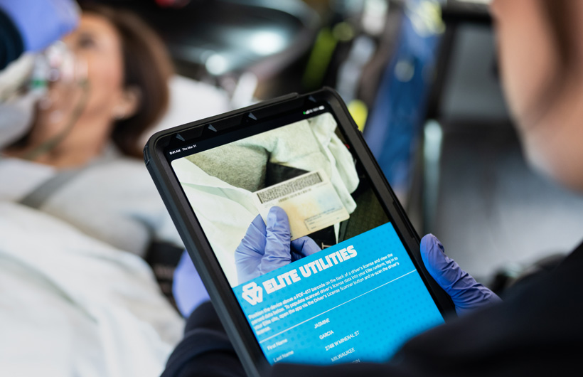 Un ambulancier utilise l’app Elite Utilities sur iPad pour scanner le permis de conduire d’une patiente allongée sur un brancard