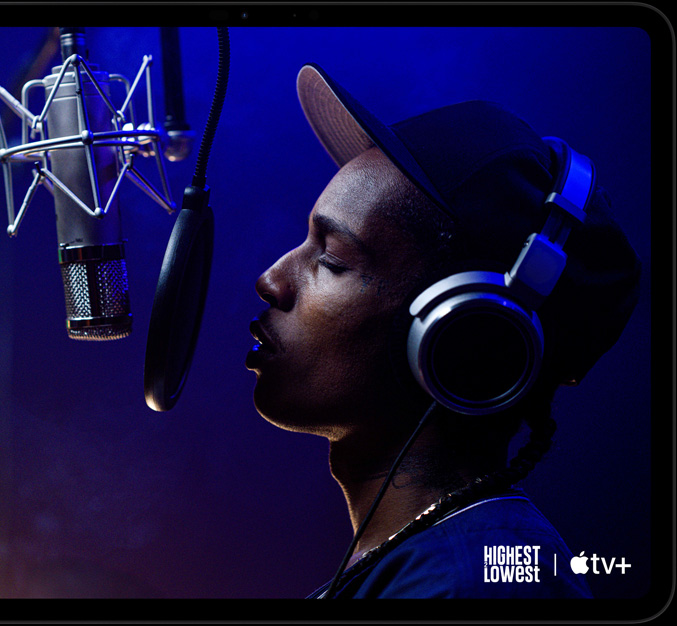 iPad Pro i space black vist forfra i vandret position, afrundede hjørner, sort skærmkant, på skærmen afspilles en scene i Apple TV+ fra Apple Original-filmen Highest 2 Lowest med ASAP Rocky som Yung Felon, der rapper ind i en mikrofon